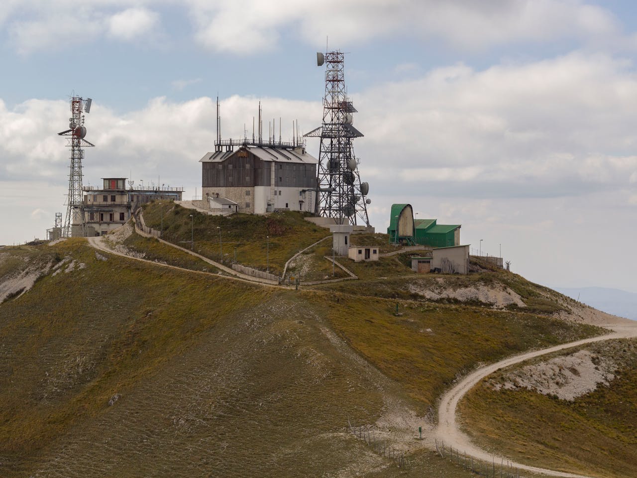 Remote hilltop in Lazio with communication towers and scenic views under a cloudy sky.