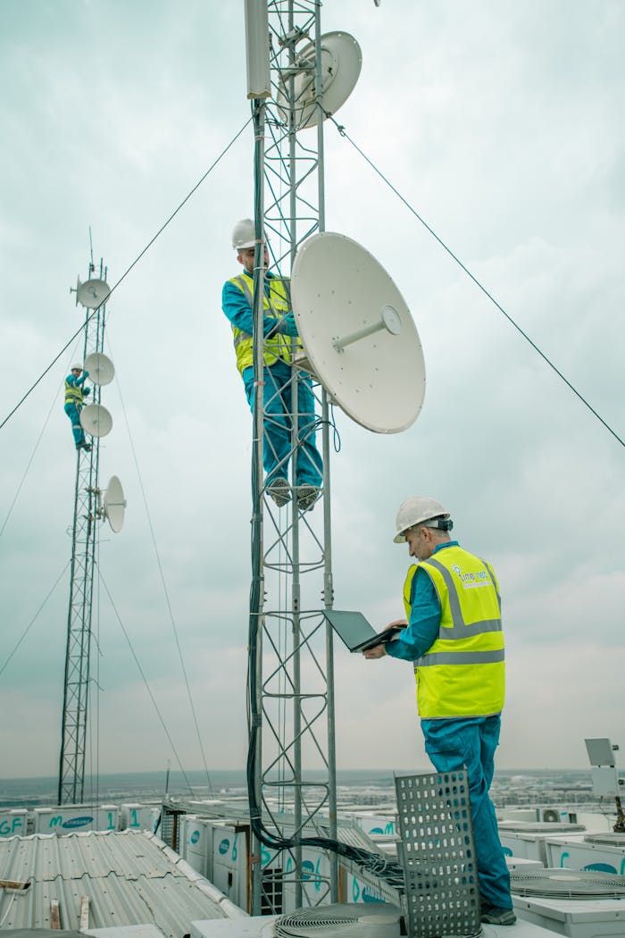 Workers in reflective vests install satellite dishes on towers in Shaqlawa, Iraq.